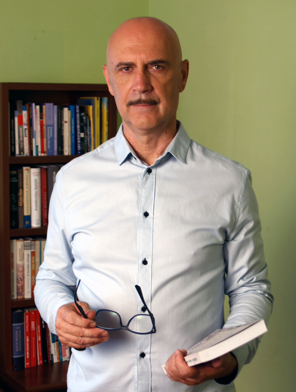 Miro Božić sjedi u uredu ispred police s knjigama, u opuštenoj atmosferi.